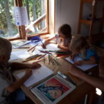 Tre barn och en vuxen som ritar
