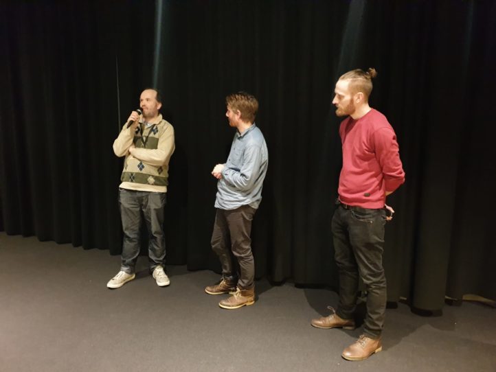 tre män står på en scen och pratar